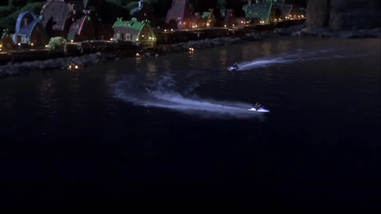 Two jet skis cross a harbor at night